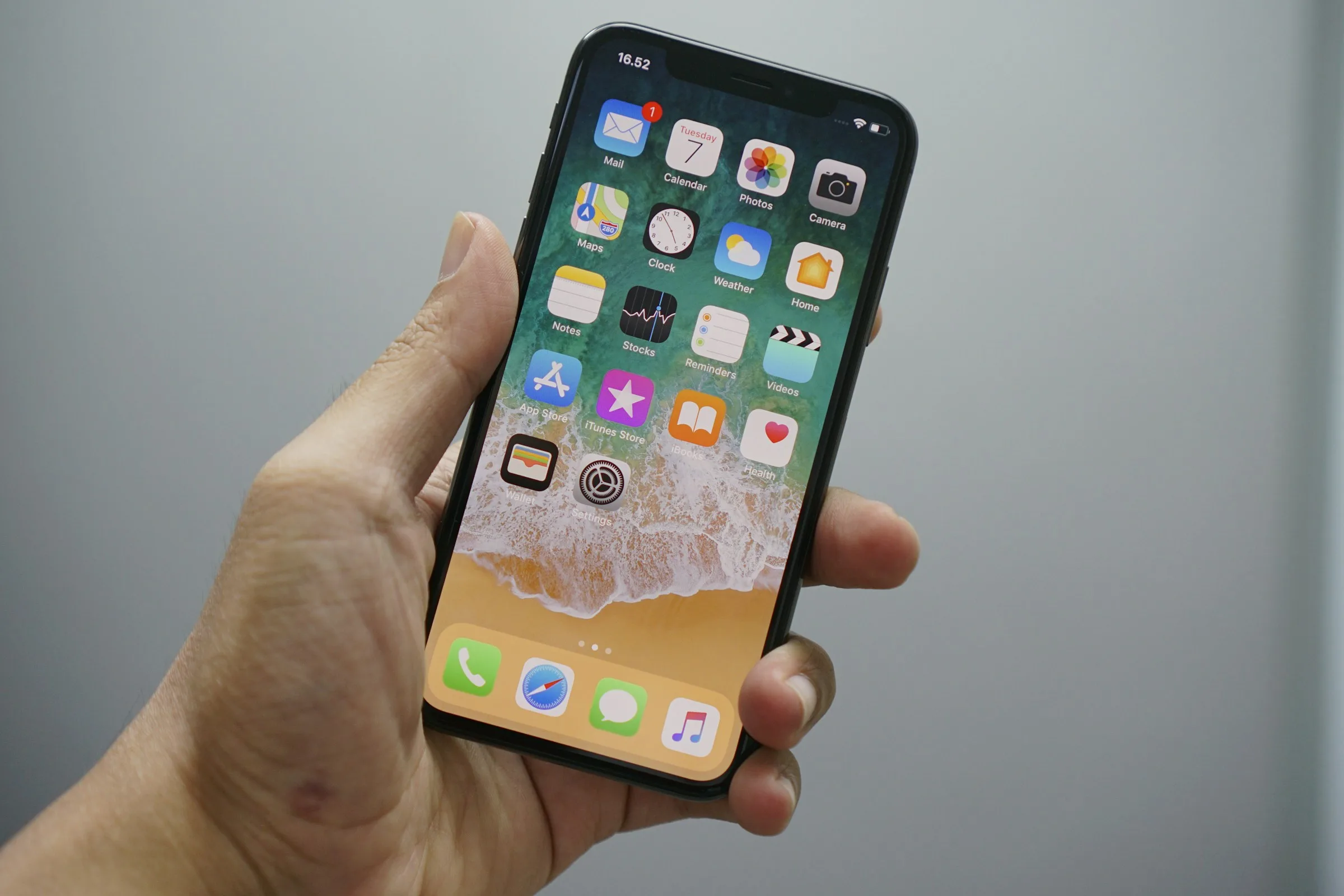 Рука держит iPhone с открытым домашним экраном
